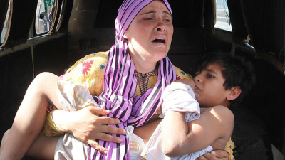 A Syrian woman carries her injured son, who was shot by the border guards as the pair crossed a river from Syria to Lebanon. UN chief Ban Ki-moon declared "civil war" in Syria. (PHOTO: AP)
