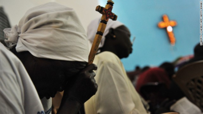 A Sudanese woman holds a cross as she prays. (PHOTO: CNN)