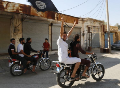A resident of Tabqa city touring the streets on a motorcycle waves an Islamist flag in celebration after Islamic State militants took over Tabqa air base, in nearby Raqqa city August 24, 2014. (PHOTO: Stringer/Reuters).