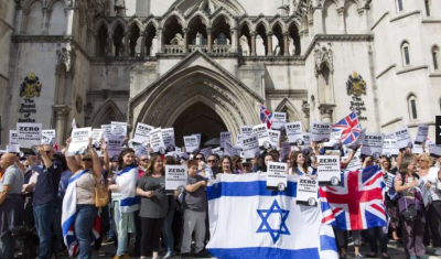 People hold placards and Israeli and Union flags outside the Royal Courts of Justice as Jewish groups rally in London on August 31 (PHOTO: AFP).