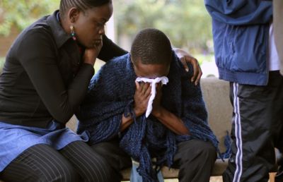 Stephen, centre, who lost his father in Saturday's attack at the Westgate Mall in Nairobi, Kenya, is comforted by relatives as he waits for the post mortem exam at the city morgue Monday, Sept. 23, 2013.