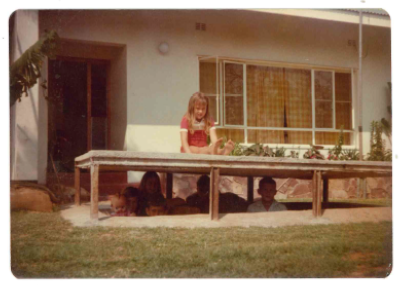 Young Debbie perched on a bomb shelter in front of the house while the other kids play in the shelter.