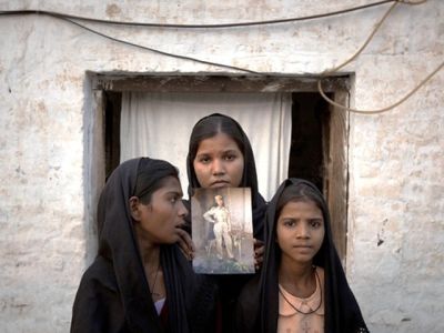the-daughters-of-asia-bibi-with-an-image-of-their-mother-standing-outside-their-residence-in-sheikhupura-on-november-13-2010