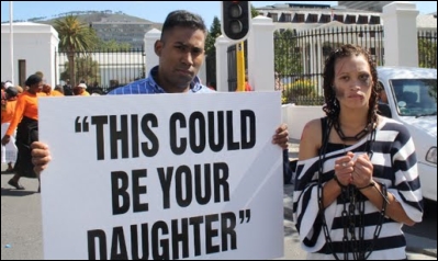 A poster and a protestor in chains and tattered clothes gets the message across: your daughters are at risk to the evil of human trafficking as long as there is no legislation against it.