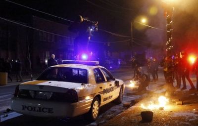 A protester jumps on a Ferguson police car set on fire by protesters in Ferguson, Missouri, November 25, 2014. (PHOTO: Reuters/Jim Young)