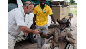 Peter Dawson (left) presents a wheelchair to a delighted 98 year old man who is paralysed from the waist down. The man has been lame for decades and this is his first wheelchair.